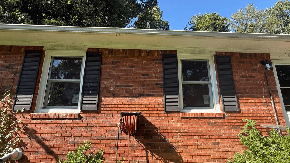 Red brick exterior with two white-framed windows and black shutters.