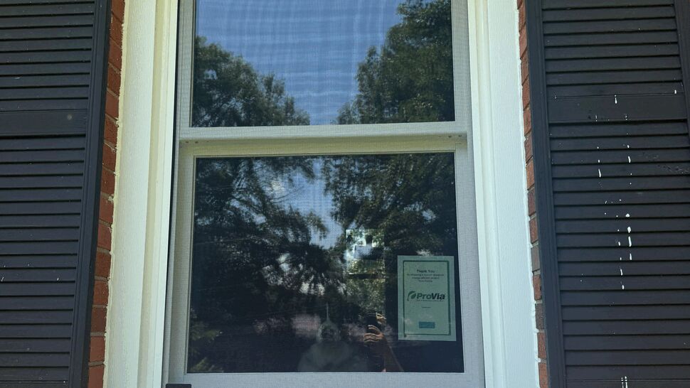 Close-up of a single white sash window with black shutters and a ProVia sticker.