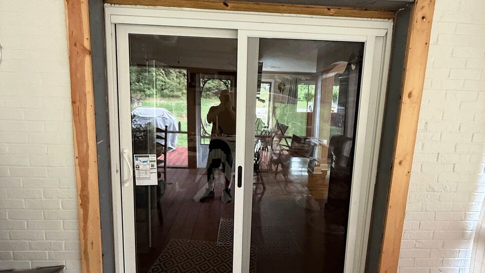 White sliding glass patio door in a porch opening with wood floor