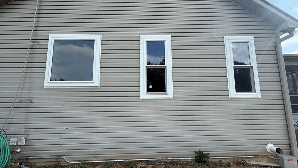 Three exterior windows in a row on beige siding