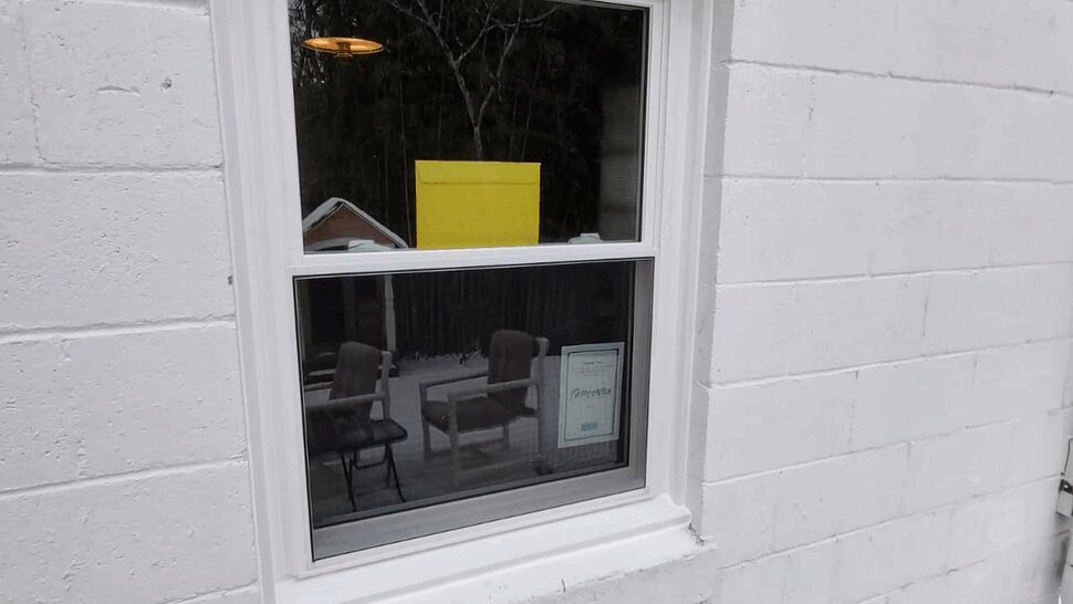 White double-hung window in a cinderblock wall with snow along the base