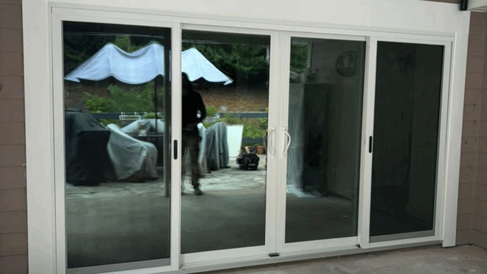 White four-panel sliding glass doors with reflective panels opening to a covered patio