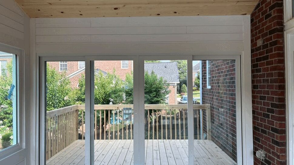 Interior view of white four-panel sliding glass door opening to a wooden deck