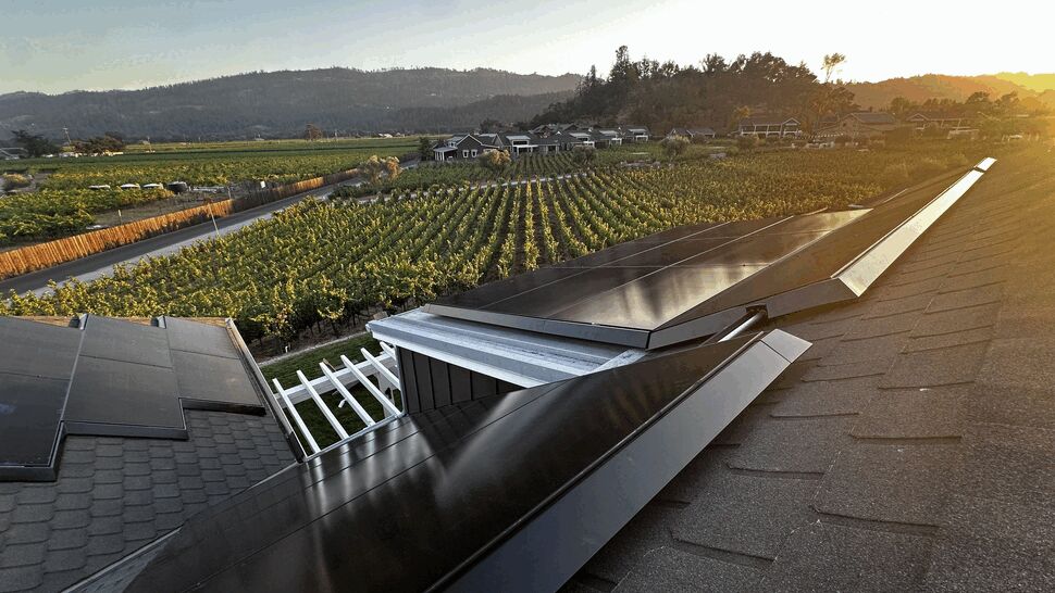 Close-up solar panel installation | Green Air Heating & Air Conditioning Inc Close-up of black solar panels installed along a roof edge with vineyard in background.