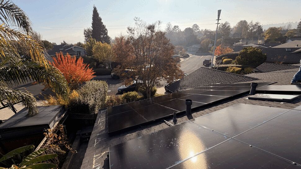 Residential Rooftop Solar Installation | Green Air Heating & Air Conditioning Inc Wide-angle view of multiple black solar panels installed on a home's roof with neighborhood vista.