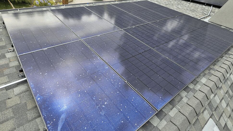 Overhead view of residential solar panels on a sloped roof with trucks below