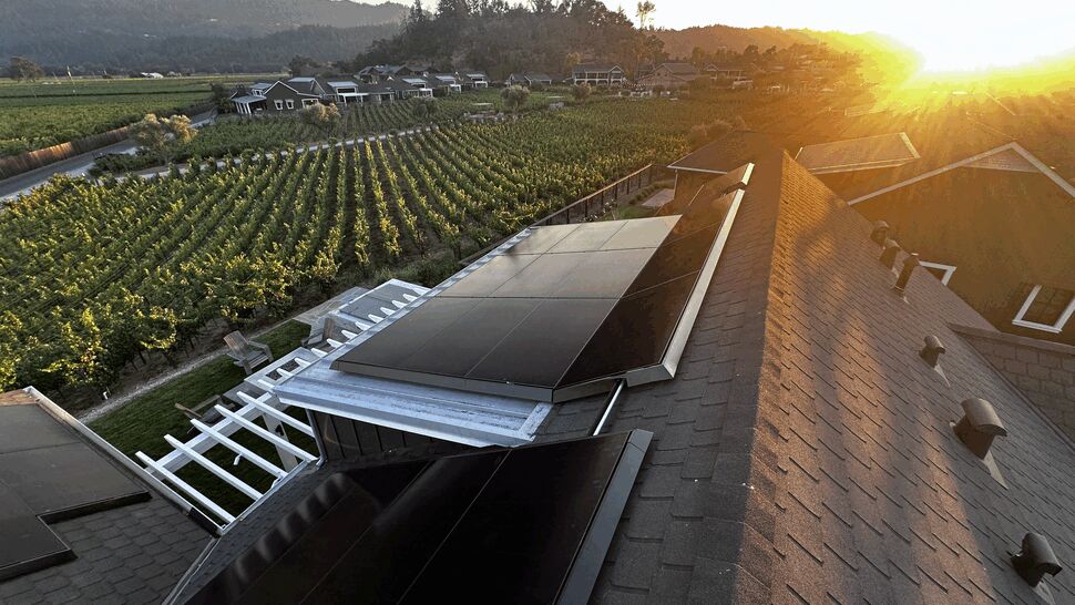 Roof-mounted solar array at sunset | Green Air Heating & Air Conditioning Inc Roof-mounted solar array over a pergola with vineyard rows beyond at golden hour.