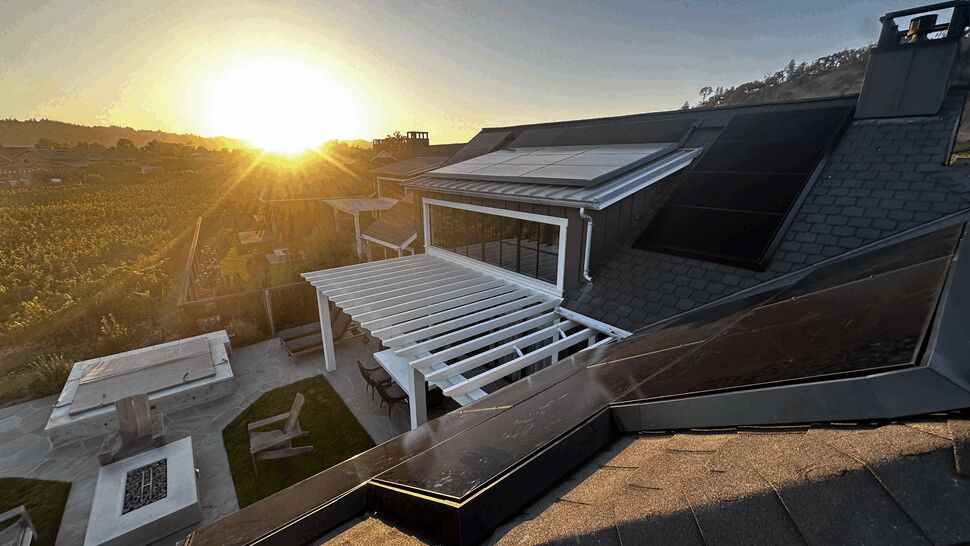 Sunset rooftop solar installation | Green Air Heating & Air Conditioning Inc Rooftop black solar panels at sunset above a backyard pergola and seating area.