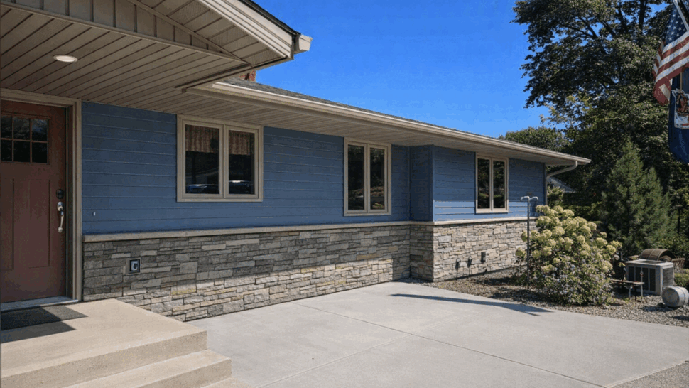 Front corner of house with blue horizontal siding and stone veneer near the entry