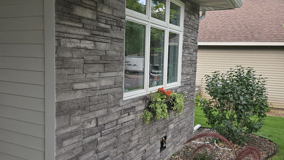 Angled Versetta Stone Siding Detail | Lutgen Companies Angled view of Versetta Stone siding along foundation with landscaping