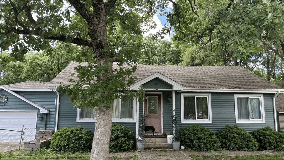 Front view of a blue-sided house with white windows, entry door, and gutters
