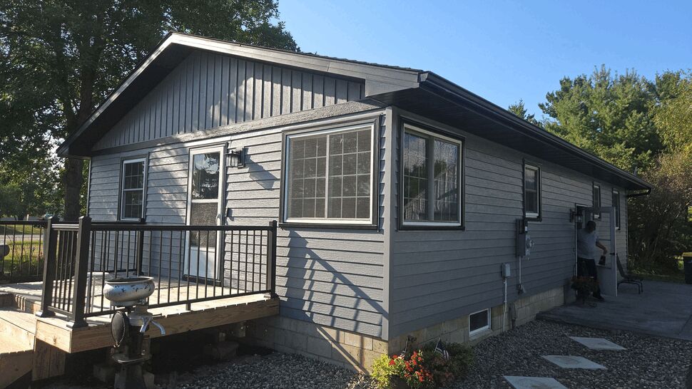 New Deck with Gray Siding | Lutgen Companies New wooden deck with black railing attached to gray-sided house