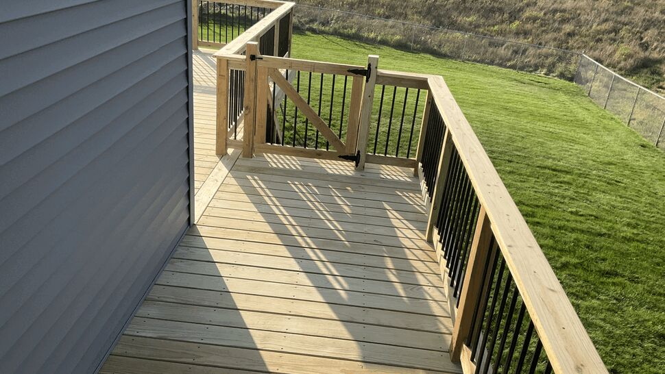 Pressure-treated deck off a sliding patio door with aluminum spindle railing and stair access, Rockville MN