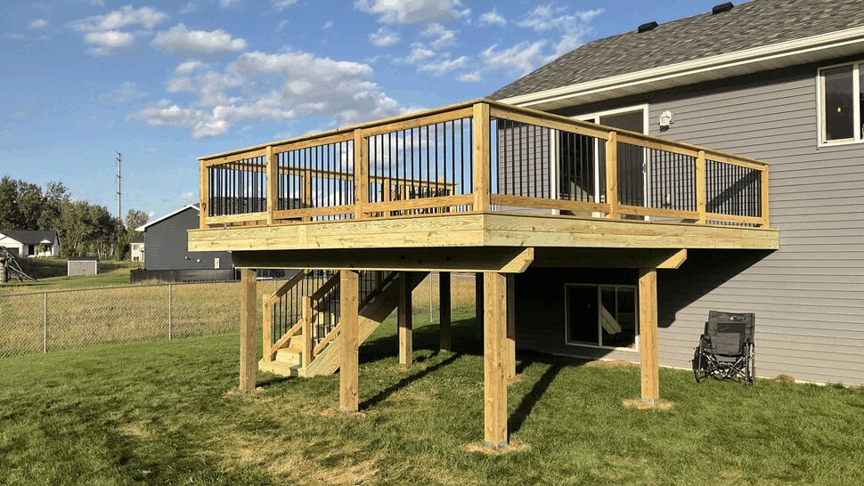 New elevated green treated deck with black aluminum spindles and 6x6 posts on a split-level home in Rockville, MN