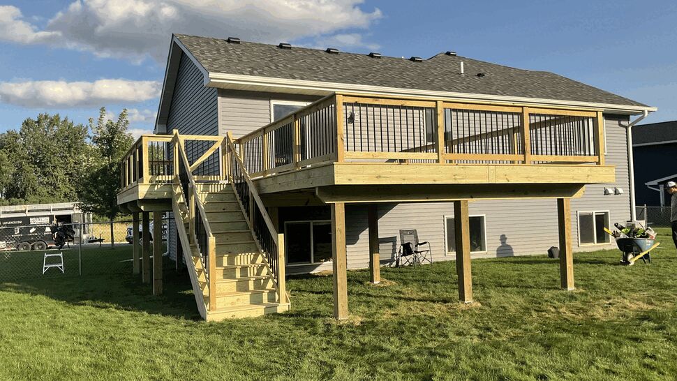 Green treated deck with black aluminum spindle railing and full staircase built by Lutgen Companies in Rockville, MN