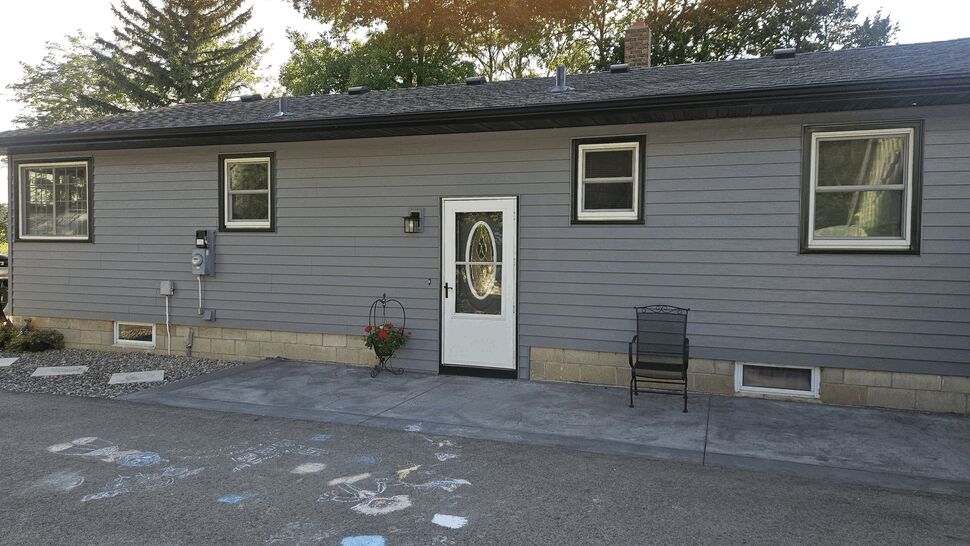 Updated Entry Door and Siding | Lutgen Companies White oval glass front door set in gray siding exterior