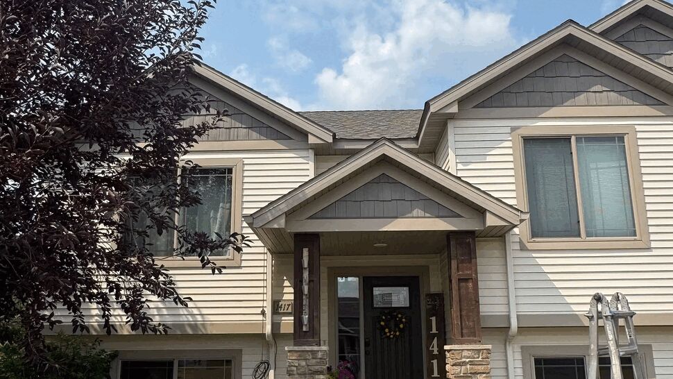 Front entry porch with dark door, stone columns, and siding