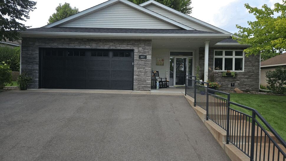 Full Front with Stone and Entry Door | Lutgen Companies Full front view of house with Versetta Stone siding, black garage and covered entry