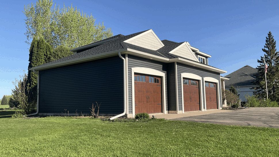 White Gutters and Downspouts on Garage | Lutgen Companies Side of garage with white gutters and downspout on blue siding