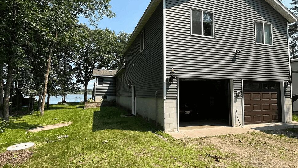 Two-story gray home with vinyl siding and garage doors near lake