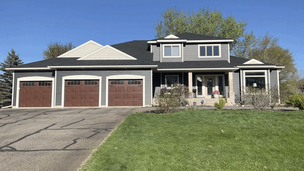 Dark Shingle Roof on Gray Home | Lutgen Companies Gray house with dark shingle roof and three-car garage