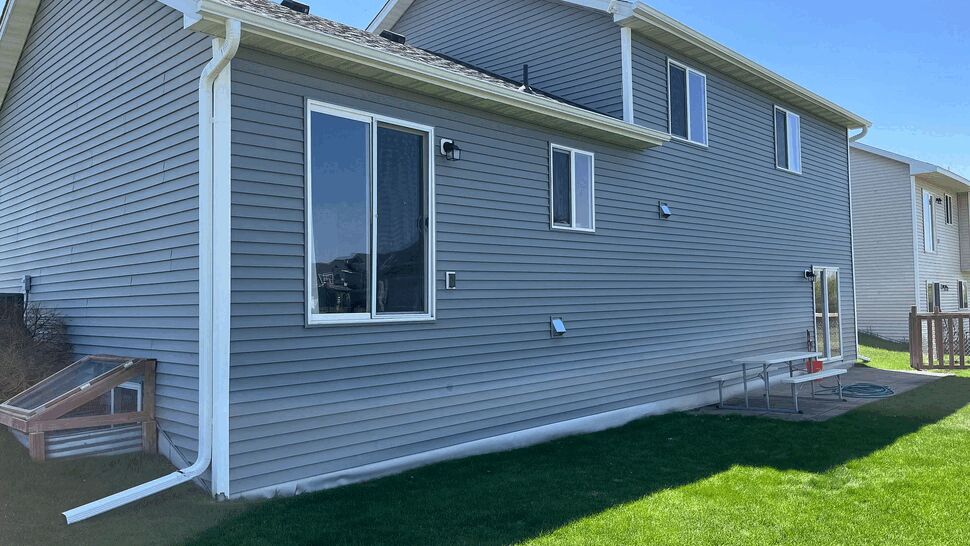 Rear exterior with gray vinyl siding and white gutters