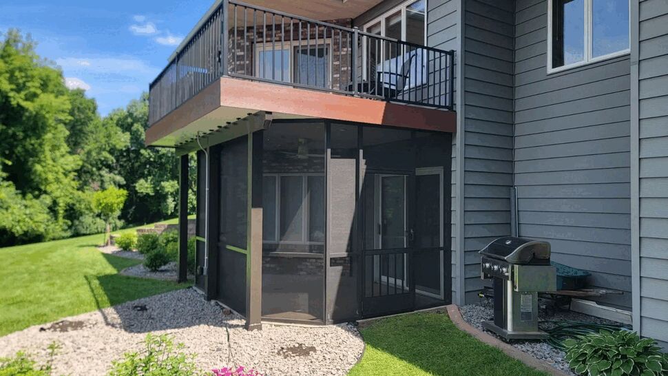 Gray siding and screened porch with lawn and grill nearby