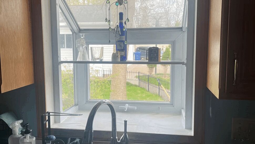 Double-bowl kitchen sink beneath a small casement window looking outside.
