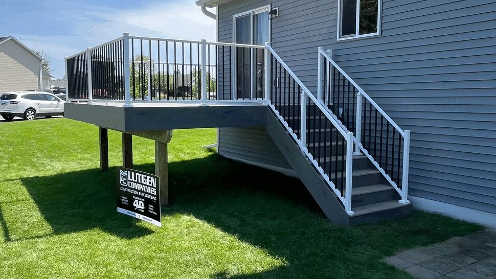 Raised deck with white railing and stairs from yard