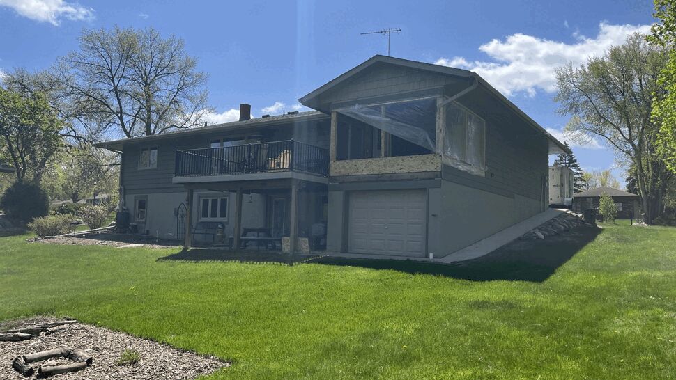 Elevated deck with black railing and a screened porch above garage