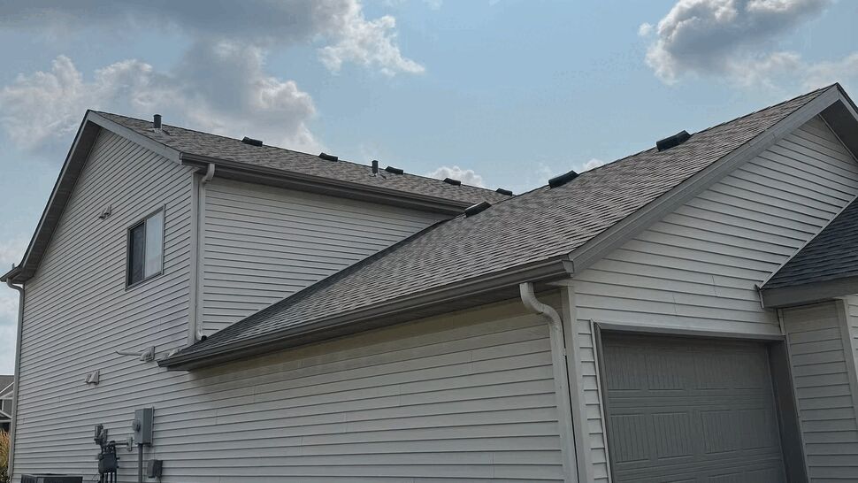 Angled view of garage roof and siding with satellite dish