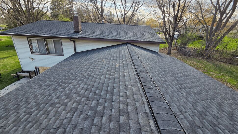 Wide view of a finished gray shingle roof on a suburban home.