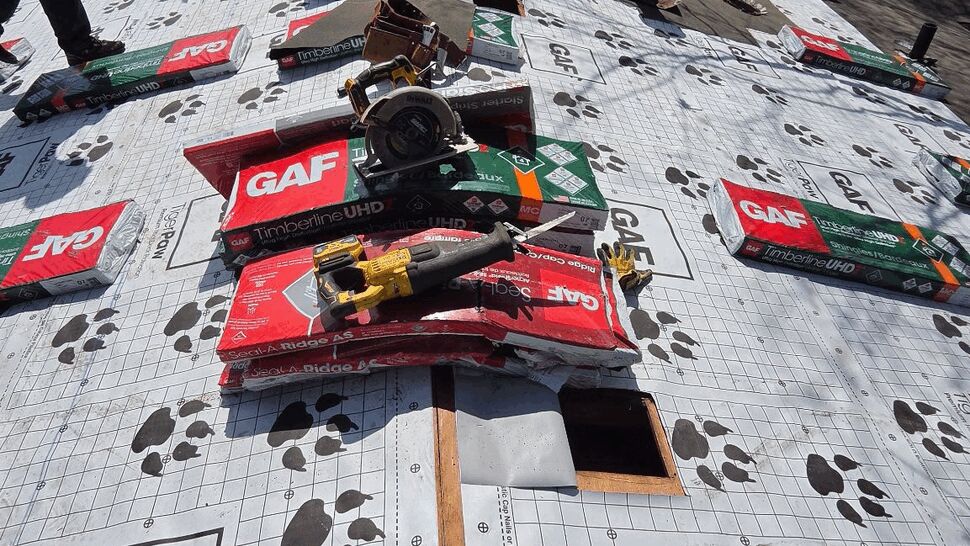 Roofing crew installing underlayment and shingles on a residential roof.