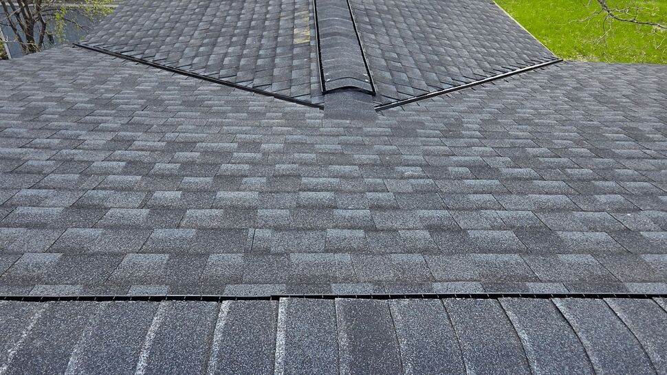 Finished asphalt shingles and ridge details across a multi-section roof.