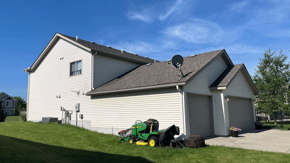 Side view of house showing garage, white siding and lawn equipment