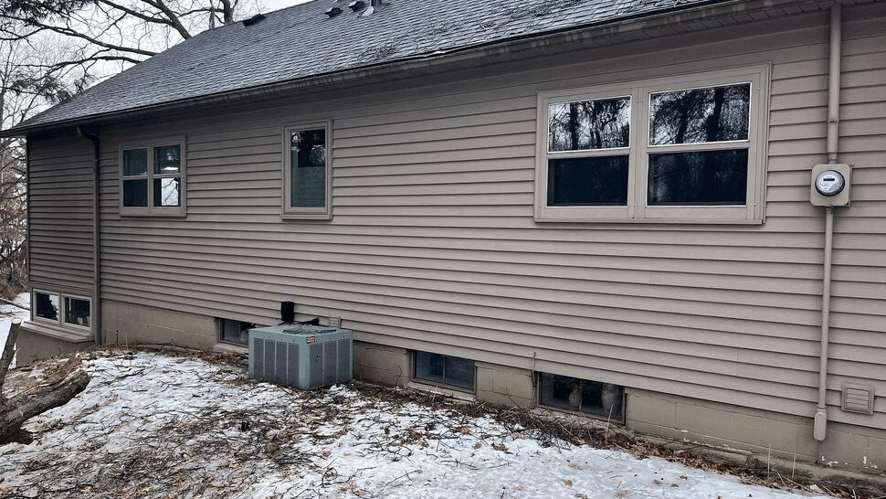 Exterior Gutters and Siding in Winter | Lutgen Companies Snow-covered yard and house exterior with gutters, siding and basement window wells.