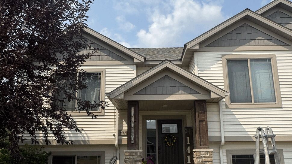 Beige vinyl siding on suburban entryway | Lutgen Companies Front two-story home with beige vinyl siding, entry porch, and ladder on the lawn