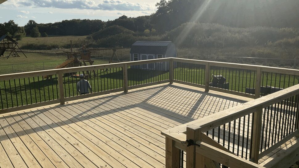 Green treated deck boards and black aluminum balusters overlooking a backyard in Rockville, Minnesota