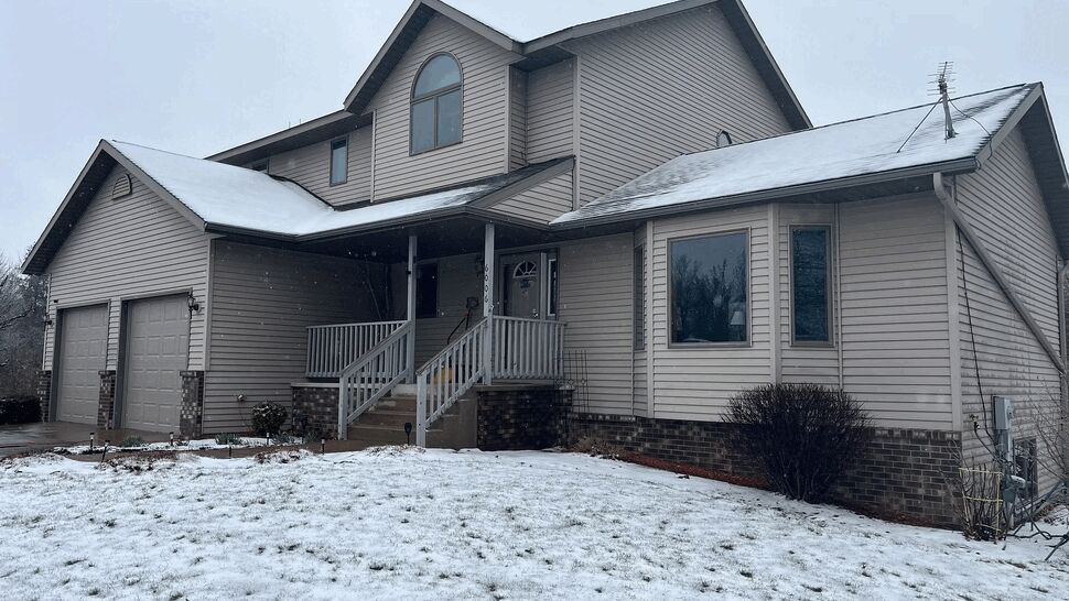 Two-story house with snow on the roof, gutters, siding and attached garage.