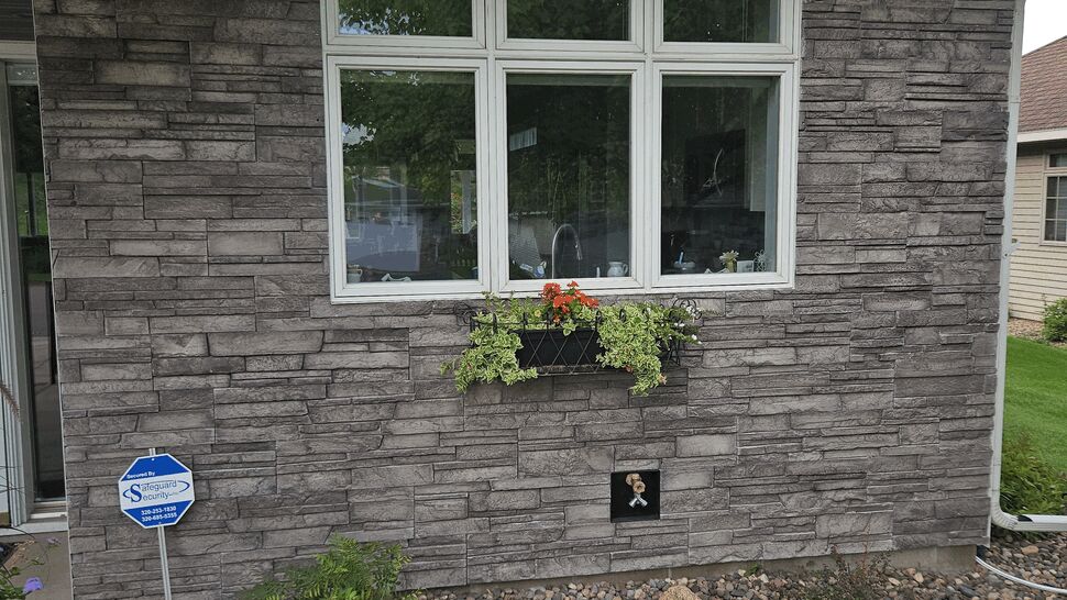 Window with Versetta Stone Siding | Lutgen Companies Gray Versetta Stone siding with white-framed window and flower box