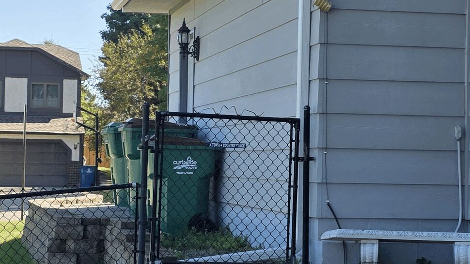 Close-up of white gutter and downspout along the eave of a gray house.