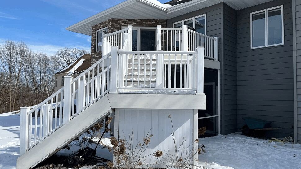 Snow-covered white deck stairs and railing at rear of house