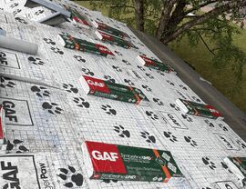 Bundles of GAF Timberline UHDZ shingles and Seal-A-Ridge staged on a roof covered in GAF TigerPaw underlayment