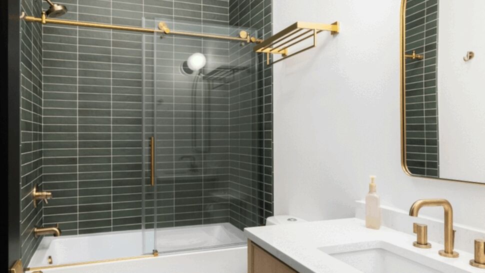 Contemporary bathroom with green subway tile shower, glass door, wood vanity and gold fixtures