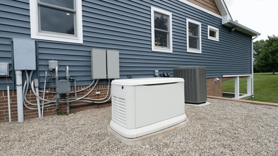 Standby generator and HVAC condenser beside blue house siding.