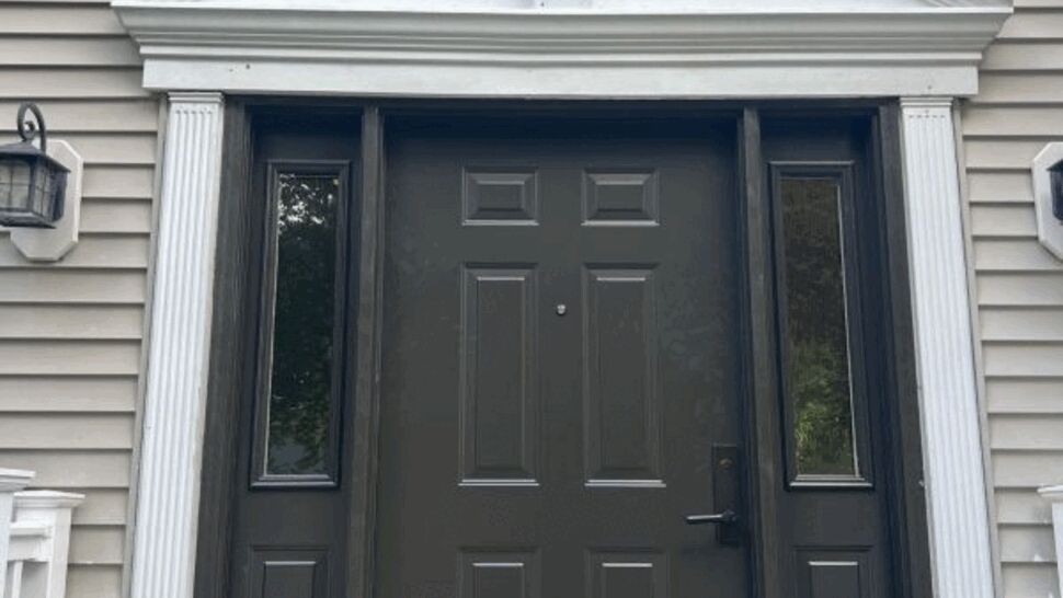 Black front door flanked by sidelights and white decorative pediment