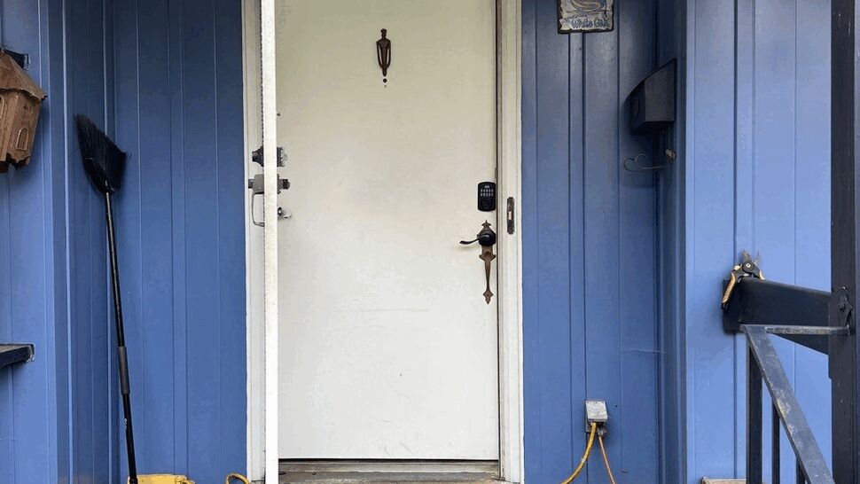 Blue-sided front porch with white storm door open, brick steps and entry mat