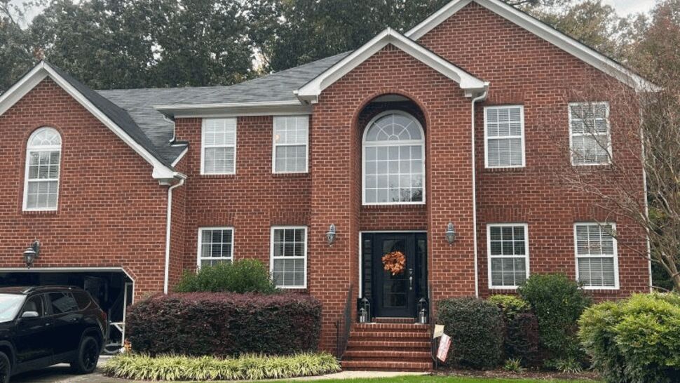 Front view of brick home with shingle roof, white trim, and gutters