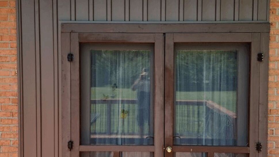 Brown double French-style screened doors with vertical siding above and red deck below