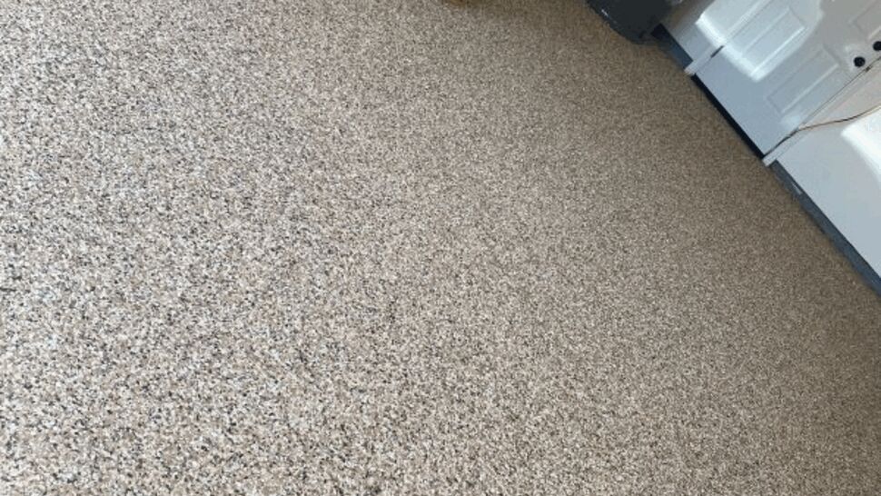 Wide view of epoxy flake garage floor with wooden steps and utilities.